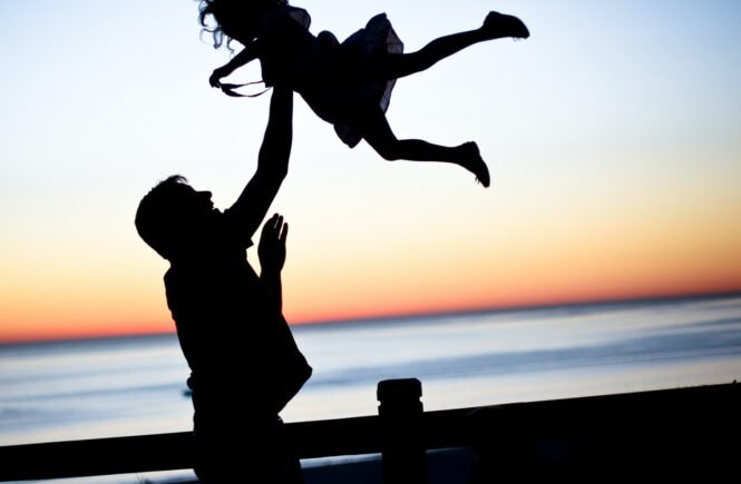 silhouette of man throwing girl in air