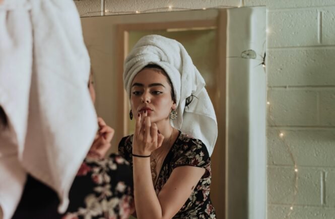 woman putting makeup in front of mirror