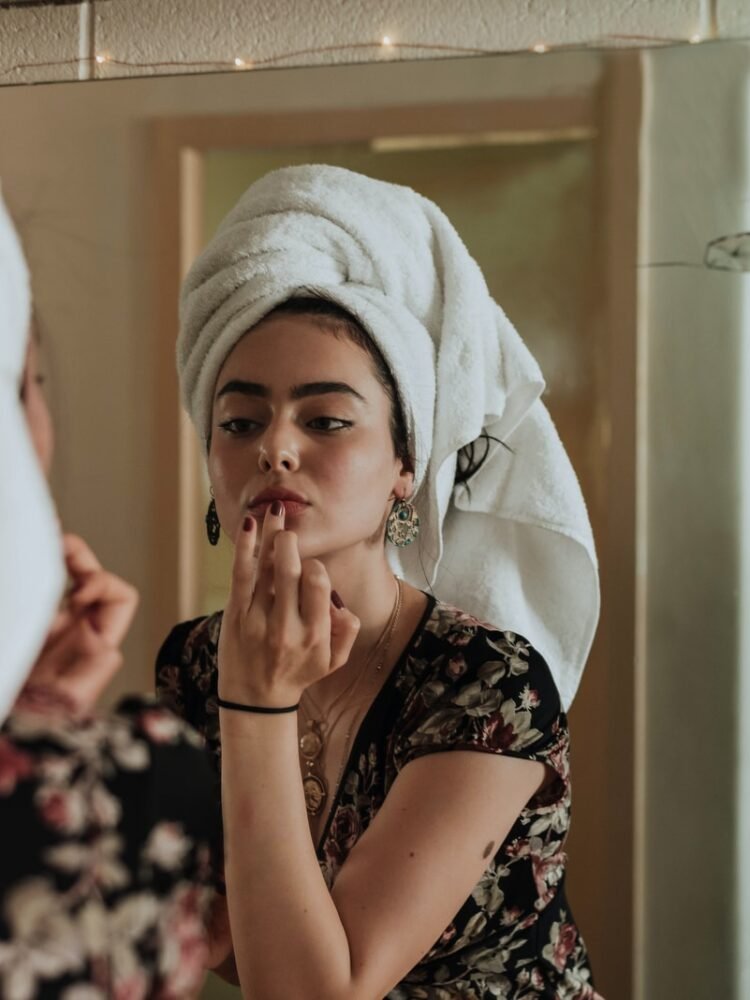 woman putting makeup in front of mirror