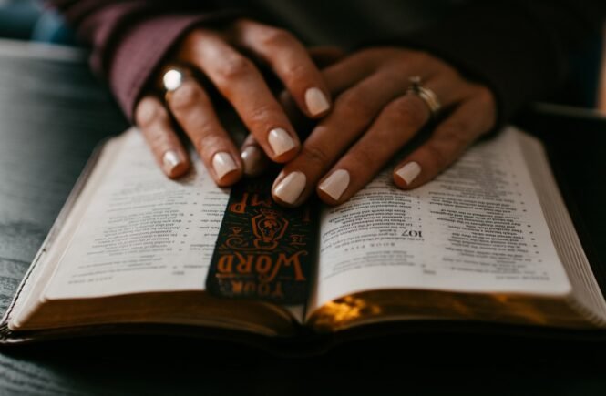 person wearing silver ring on ring finger on bible
