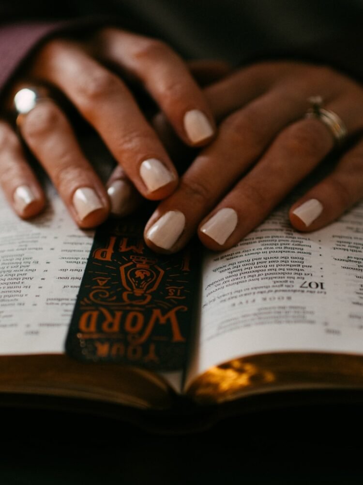 person wearing silver ring on ring finger on bible