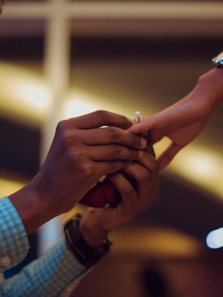 man putting ring on woman's hand